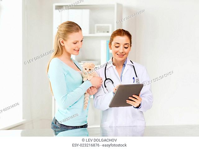 medicine, pet, health care, technology and people concept - happy woman and veterinarian doctor with tablet pc computer checking scottish fold kitten up at vet...