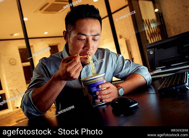Young men in the office to work overtime to eat instant noodles