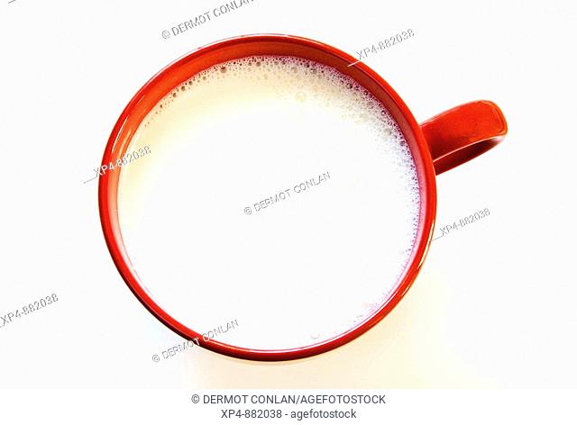 Large red mug of milk on white background photographed from above