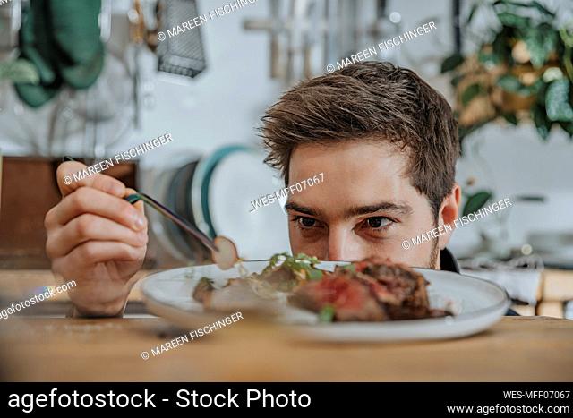 Chef concentrating while garnishing tomahawk steak with vegetable in kitchen