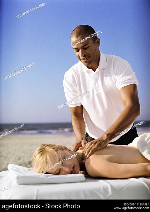 Woman receiving massage at beach