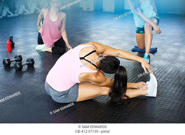 Young woman stretching leg and side in gym