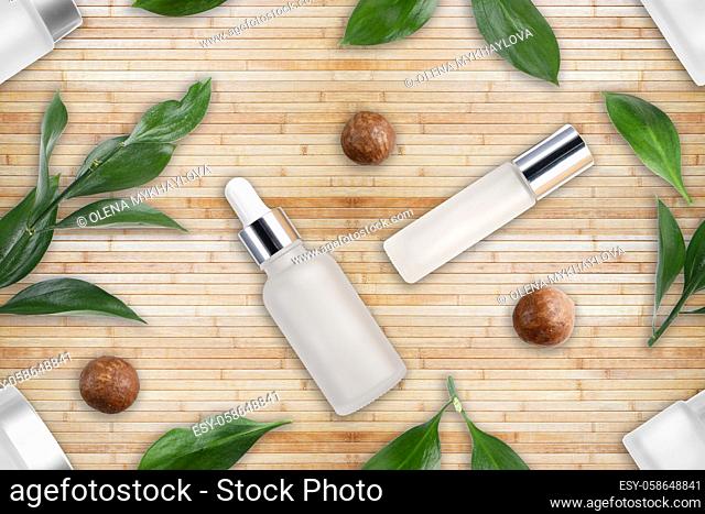 Tileable seamless flat lay background of bottles with macadamia nut cosmetics and leaves on bamboo mat. Natural cosmetics concept