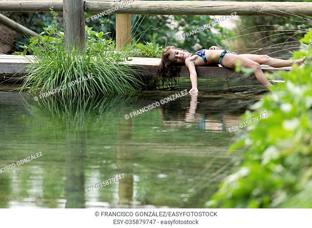 Girl lying on the footbridge of a lake. Take place in Bogarra, province of Albacete, Spain