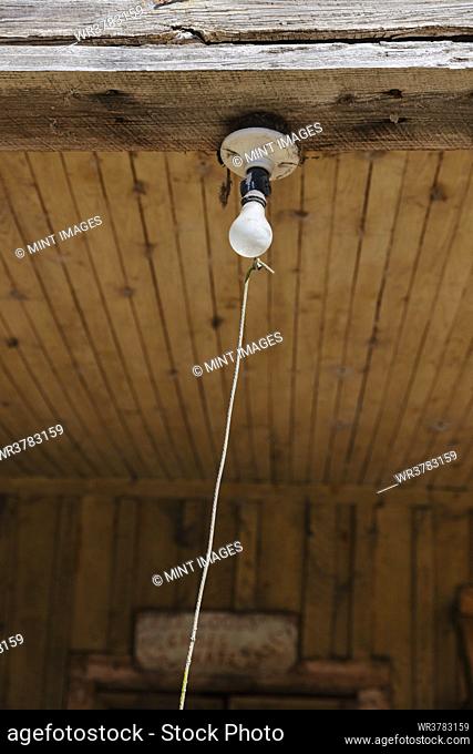 Old incandescent light bulb on a porch beam with a string pull control