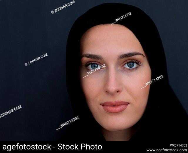 Portrait of modern young muslim woman in black abaya. Arab girl wearing traditional clothes and posing in front of black chalkboard