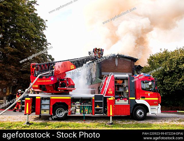 23 September 2022, Schleswig-Holstein, Borgdorf-Seedorf: Firefighters extinguish a burning barn with the help of a turntable ladder