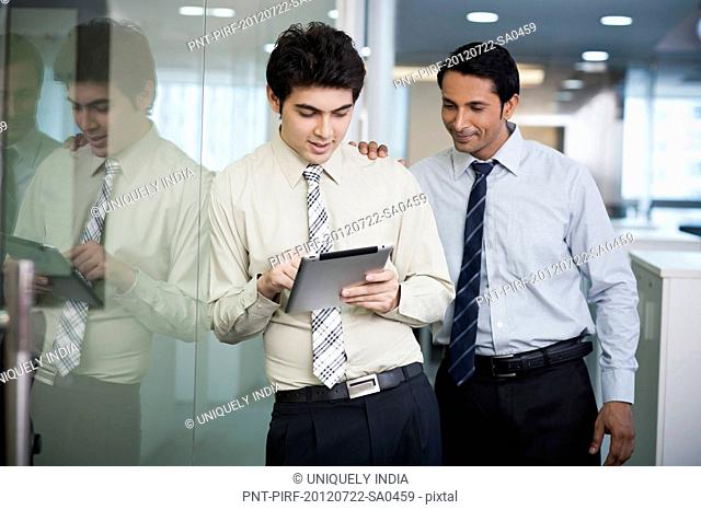 Businessman using a digital tablet with his colleague standing beside him