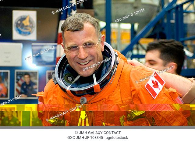 Canadian Space Agency astronaut Dafydd R. (Dave) Williams, STS-118 mission specialist, receives assistance in donning a training version of his shuttle launch...