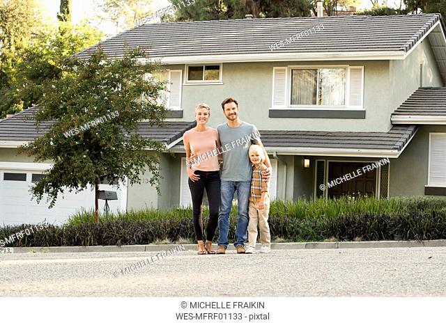 Portrait of smiling parents with boy standing in front of their home