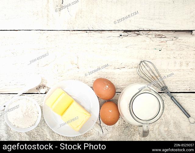 Ingredients for the preparation of bakery products: flour eggs butter milk. Top view. Rustic style. White wooden background