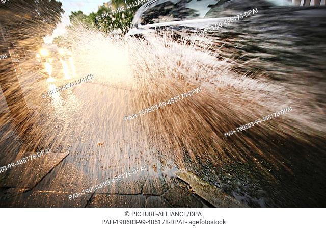 03 June 2019, Duesseldorf: A car drives in the state capital through a puddle of water on the road. A low pressure area brings hot and humid air from the...