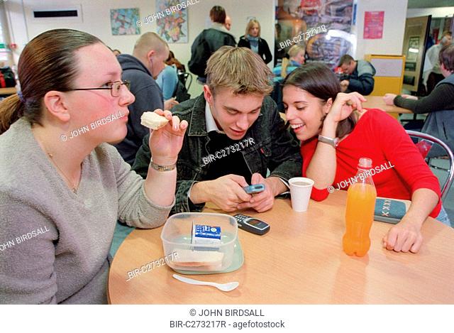 Teenage girl with physical disability sitting at table with friends in college canteen