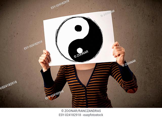 Woman holding a paper with a yin-yang on it in front of her head