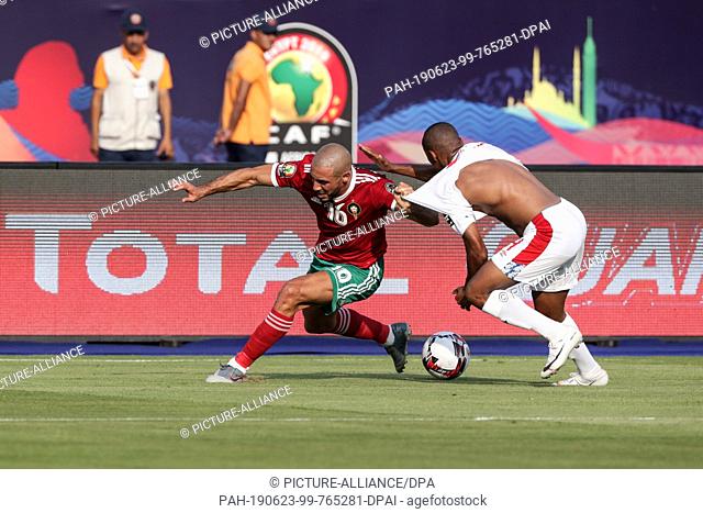 23 June 2019, Egypt, Cairo: Morocco's Noureddine Amrabat (L) pulls the shirt of Namibia's Riaan Hanamub during the 2019 Africa Cup of Nations Group D soccer...