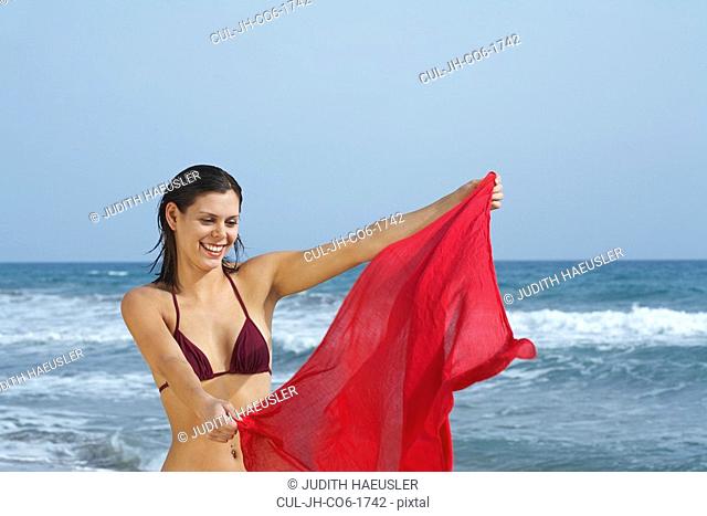 Woman waving sarong in wind on beach