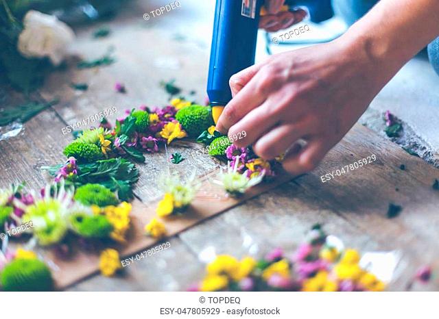 Florist making flower decoration with letters and glue. Indoors natural light shot with small depth of field