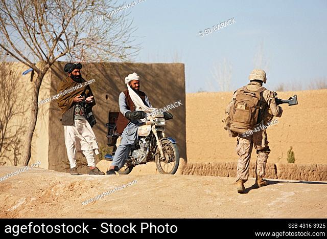 Local Men Watch a U.S. Marine Crossing a Dirt Road During a Combat Operation in Afghanistan's Helmand Province
