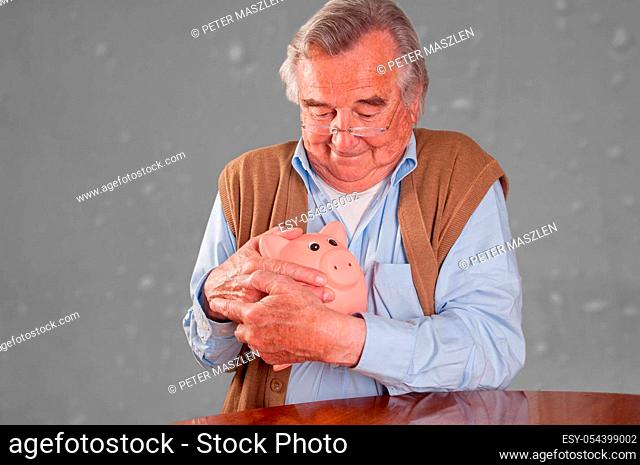 Portrait of senior man holding his piggy bank, isolated grey background