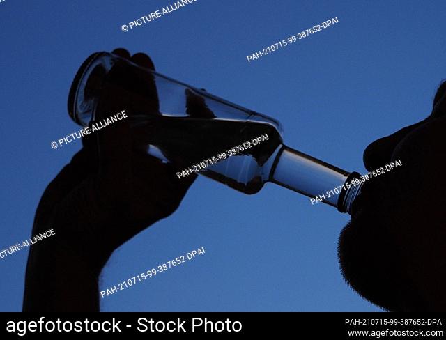 14 July 2021, Brandenburg, Potsdam: A man drinks from a small bottle of schnapps in the evening. In Brandenburg, the effects of the Corona pandemic are...