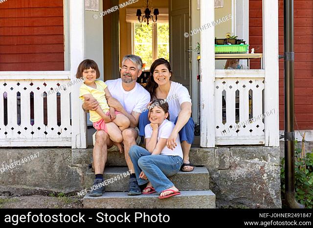 Parents with two daughters sitting in front of house