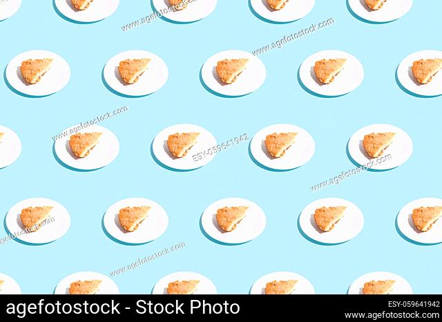 pattern of apple pie slices on white plate on blue background. trendy food pattern with shadow. High quality photo