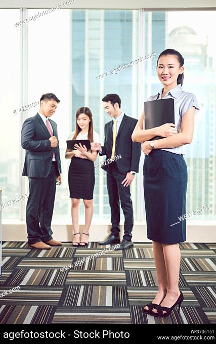 Smiling young businesswoman standing in front of colleague discussing on digital tablet