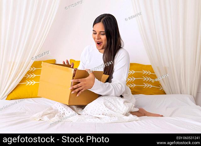 Indian girl checking parcel with excitement shopping through online