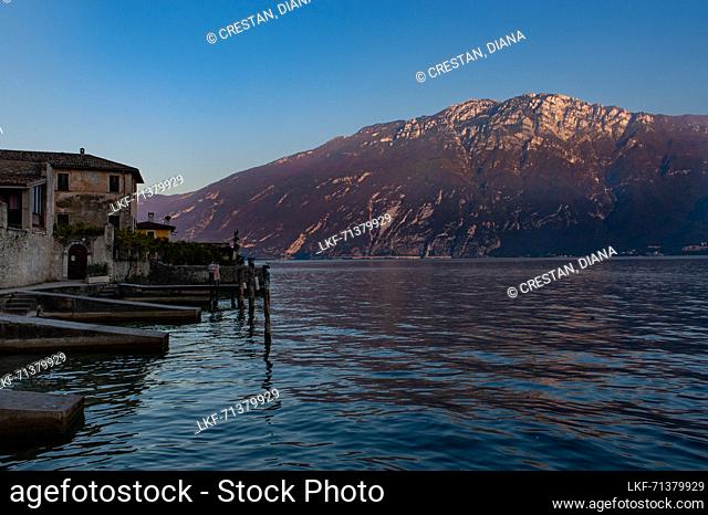 Two tourists await the sunset on the shore of Lake Garda in Limone sul Garda
