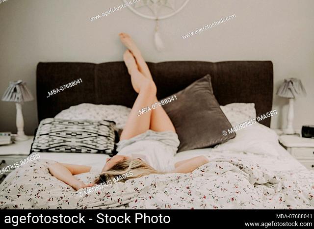 Woman lying relaxed in bed, legs up