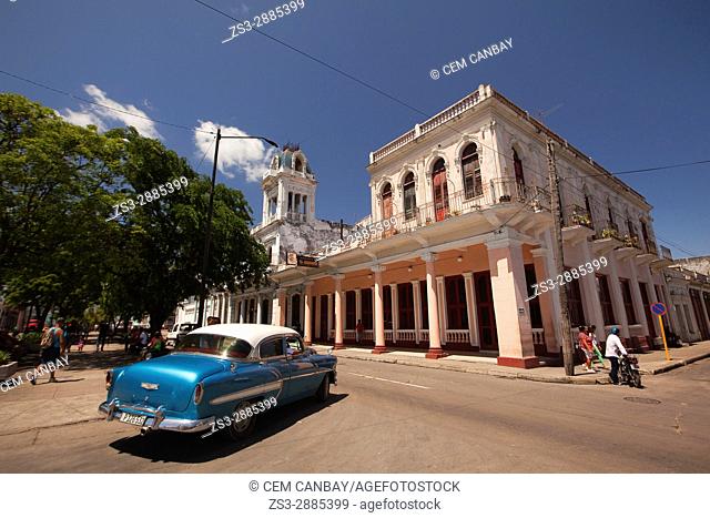 View to the colonial buildings at the main avenue Prado at the town center with an old American car in the foreground, Cienfuegos, Cienfuegos Province, Cuba