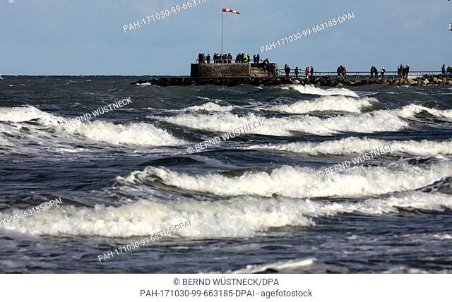 After the heavy autumn storm 'Herwart' the Baltic Sea is still whipped up in Warnemuende, Germany, 30 October 2017. The sun attracts strollers to have a walk on...