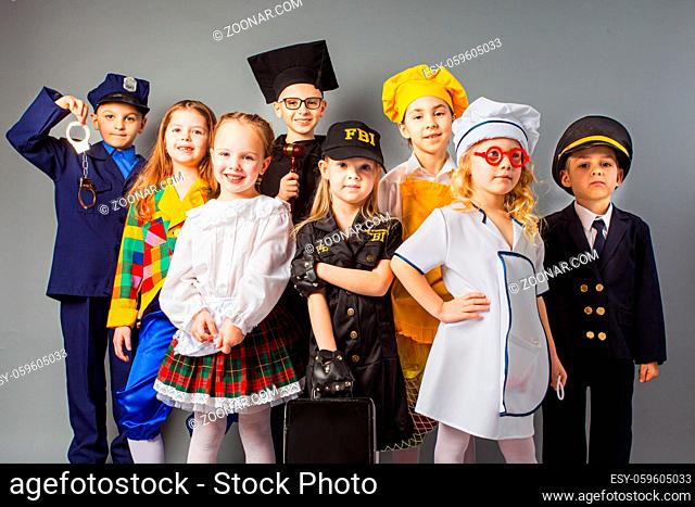 Group of school children dressing up as professions. Future education. Happy friends dressed as doctor, cook, judge, policeman, agent fbi and singer