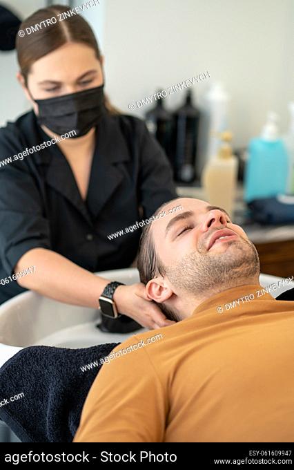 Beauty salon. Female hairdresser washing hair to the customer
