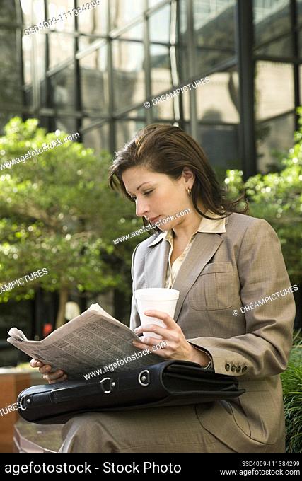 Hispanic businesswoman reading newspaper