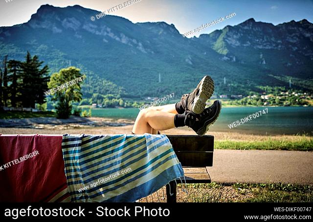 Legs of woman wearing hiking boots relaxing on bench with towel