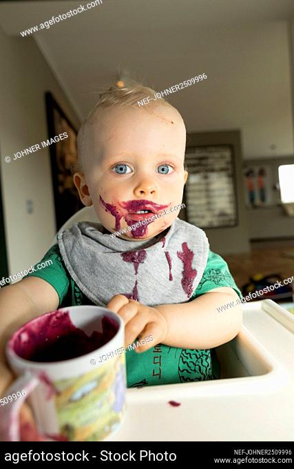 Portrait of messy baby boy eating berry smoothie