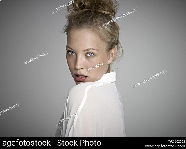 Portrait of young woman against grey background, close up