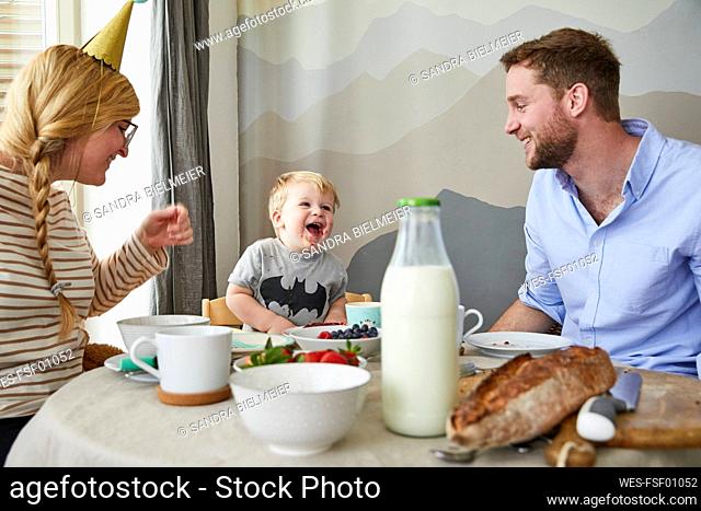 Portrait of little boy having fun with his parents at breakfast table