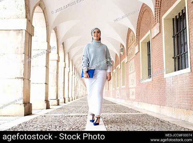 Young woman wearing headscarf walking at corridor