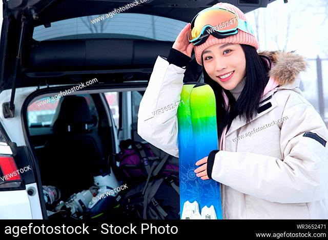 Car trunk beside the young woman holding a snowboard