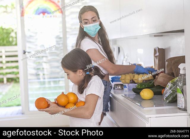 daughter helps mom (wearing a mask) in the kitchen