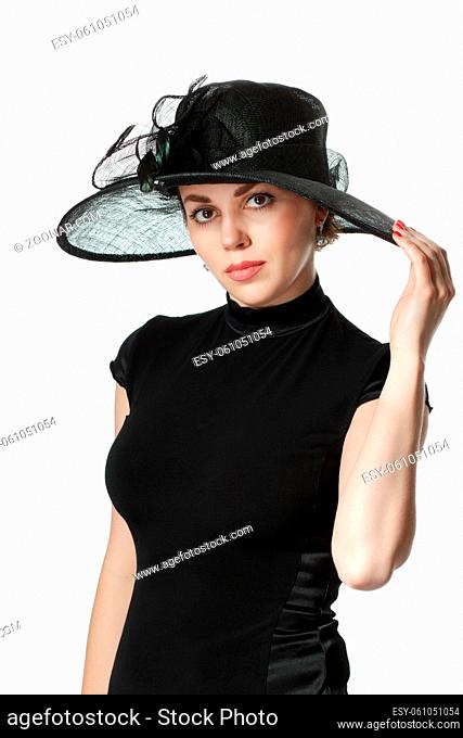 Portrait of a beautiful woman in a black dress and hat standing and holding a hat isolated on white background