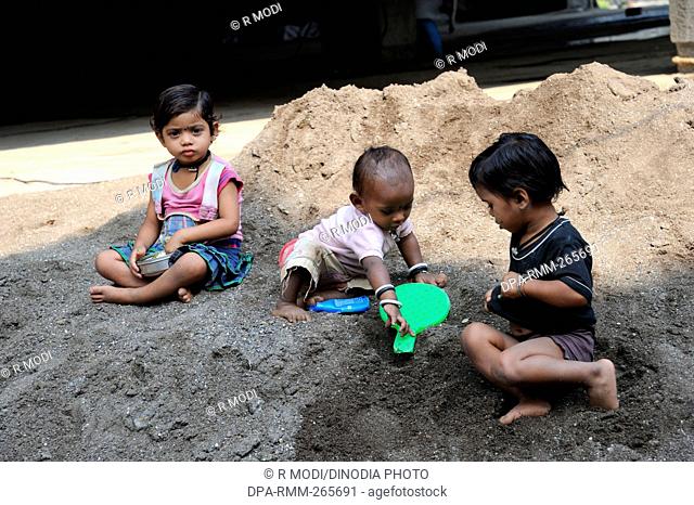 children playing in sand at building construction site, Pune, Maharashtra, India, Asia