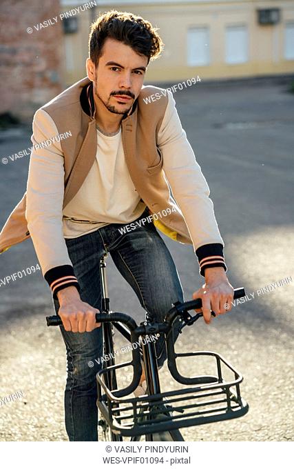 Portrait of young man riding commuter fixie bike in the city