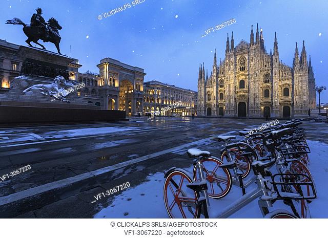 Bicycles parked in PIazza Duomo during snowfall at dusk. Milan, Lombardy, Northern Italy, Italy
