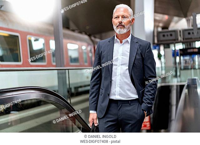Mature businessman on an escalator at the train station