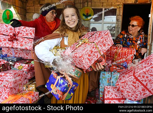 16 December 2023, Saxony, Schkeuditz: Anuk (M) stands with small and large Christmas parcels at the Zonda Klub Leipzig stand at the Victorian Christmas market...