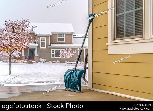 Snow shovel against snow covered landscape in Utah. The snow pusher is leaning on the wall of a home in Daybreak, Utah