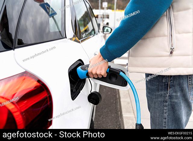 Man plugging charger in electric car